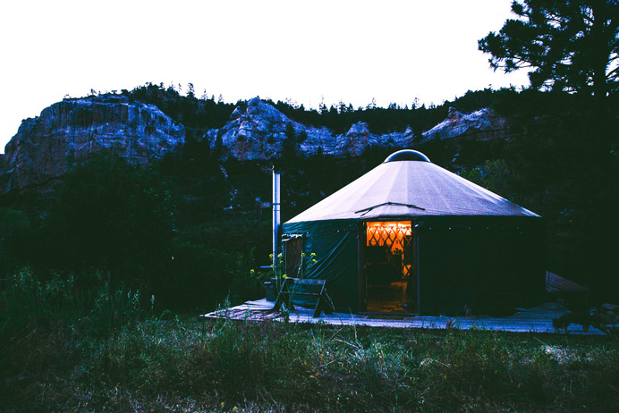 a green yurt sitting in front of a mountain